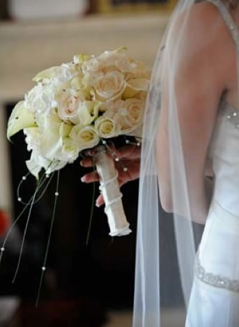 Bride holding a lush bouquet at an outdoor wedding